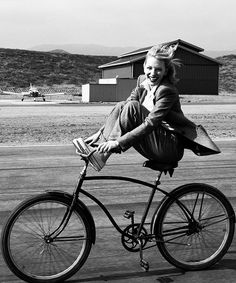 a woman riding on the back of a bike with her legs spread out and smiling