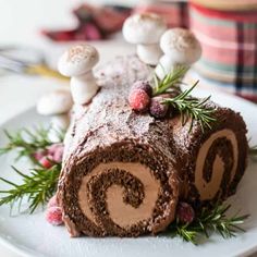 a chocolate roll on a white plate with mushrooms and greenery around the edges, ready to be eaten