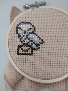 a cross - stitch owl is sitting on top of a piece of cloth