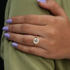 a woman's hand with purple nails and a ring on her left hand, wearing a green shirt