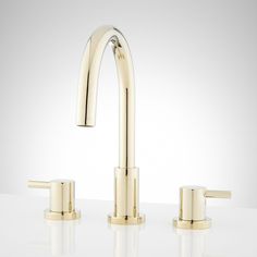 two gold faucets on a white counter top