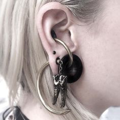 a close up of a person with ear piercings and an animal on the hoop