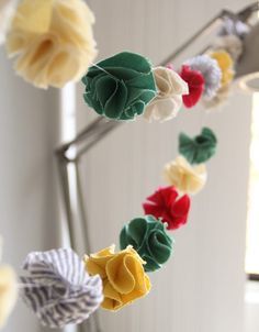 several different colored fabric flowers hanging from a metal rack in a room with white walls