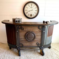 an old dresser with a clock on the wall above it and a camera in front of it