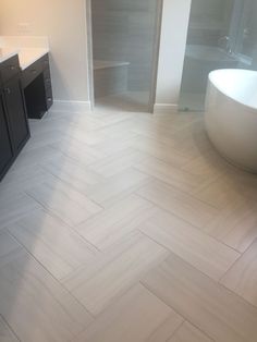 a bathroom with a tub, sink and large mirror