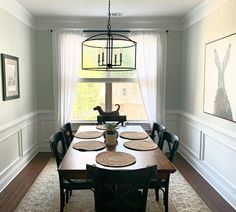 a dinning room table with place mats on it in front of a large window