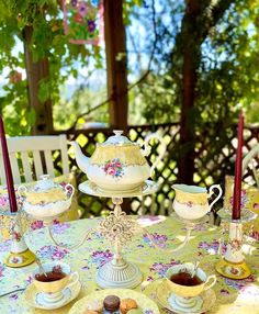 a table topped with plates and cups filled with cake next to teacups on saucers