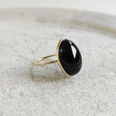 This stunning ring is set in 14k Solid Yellow Gold with Natural Black Onyx with utmost precision. It is a unique statement gemstone ring for nearly every occasion and is completely hassle-free jewelry. ITEM DETAILS: *  GEM: Black Onyx * GEM SIZE: 13X18.5mm * GEM SHAPE:  Oval *  Gem weight: 13.24 carats * Gold Purity: 14KT  * Gold Weight: 1.39 gram * Total Weight of the Ring: 3.84 gram The Gold purity is guaranteed and it comes with authentic 14KT gold hallmark. Since my items are handmade, they Modern Black Oval Jewelry, Black Oval 14k Gold Rings, Black Oval Jewelry With Bezel Setting, Modern Black Jewelry With Bezel Setting, Fine Jewelry Onyx Oval Ring, Fine Jewelry Oval Onyx Ring, Minimalist Onyx Gemstone Ring, Black Round Ring With Bezel Setting, Black Cabochon Ring In 14k Gold