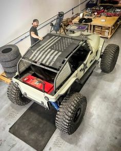 a man standing next to a jeep with an american flag on the hood and tires