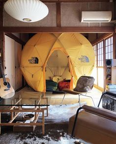 the inside of a yellow tent with two guitars and other furniture in front of it