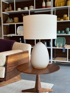 a lamp sitting on top of a wooden table next to a chair in a room