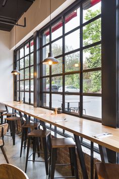 an empty restaurant with tables and stools in front of large windows that look out onto the street