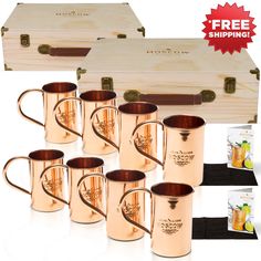 six copper colored mugs in front of a wooden box and two boxes with cards