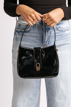 The Paige Black Vegan Leather Shoulder Crossbody Bag combines style with functionality, crafted from sleek patent vegan leather for a modern, polished look! It features a versatile design with a magnetic snap closure, ensuring easy access while keeping your belongings secure. The gold hardware adds a touch of luxury, complementing the bag's glossy finish. Equipped with a detachable chain strap, it can be worn as a shoulder bag or crossbody, offering flexible styling options. Inside, the fabric-lined interior includes a zip pocket for keeping essentials organized and within reach. Everyday Patent Leather Bag With Detachable Strap, Chic Everyday Bag With Glossy Finish, Modern Patent Leather Bag For Everyday, Modern Glossy Finish Shoulder Bag For Everyday, Chic Glossy Shoulder Bag For Everyday Use, Chic Black Patent Leather Bag, Chic Glossy Finish Shoulder Bag, Chic Patent Leather Shoulder Bag For Everyday Use, Modern Patent Leather Shoulder Bag For Everyday Use