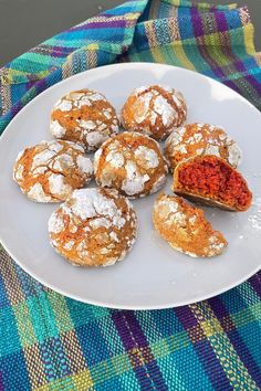 powdered sugar covered pastries on a white plate next to a blue and green table cloth