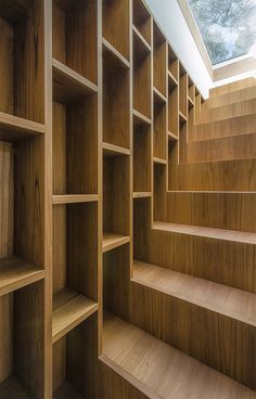 an empty wooden bookcase with stairs leading up to the skylight