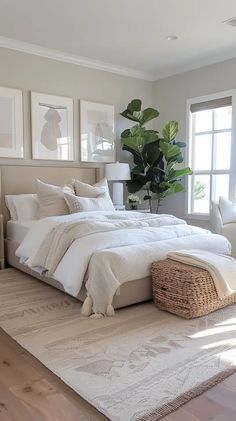 a large white bed sitting in a bedroom next to two windows and a rug on top of a hard wood floor