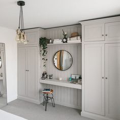 a bedroom with white walls and gray cupboards, mirrors on the wall, and a bed in front of it