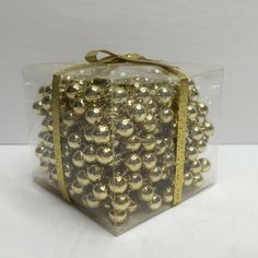 a clear box filled with lots of gold balls