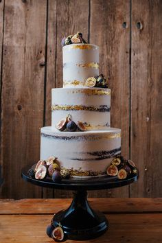 a three tiered cake with figurines on the side and gold trimmings