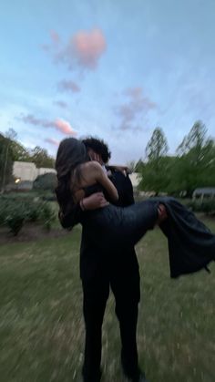 a man and woman are hugging in the grass