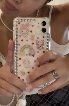 a woman is holding up her phone case with many stickers on it and she's looking at the camera