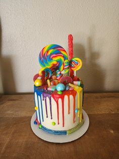 a colorful cake with candy and lollipops on it sitting on a table