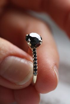 a person holding a black diamond ring in their hand