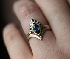 a woman's hand wearing a gold ring with a blue stone in the middle