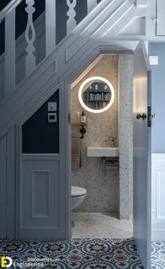 an open door leading to a bathroom with a sink and toilet under a stair case