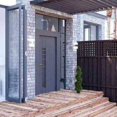 a wooden deck with a potted plant on it and a gray door in the background