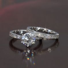 two wedding rings sitting on top of a table next to each other with diamond accents