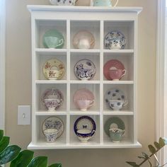 a white shelf filled with lots of different types of plates and cups on top of it