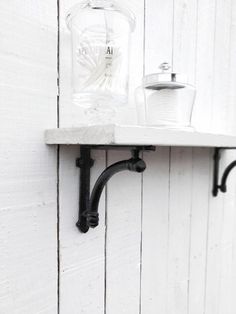 a shelf that has some jars on it and two black pipe brackets attached to the wall