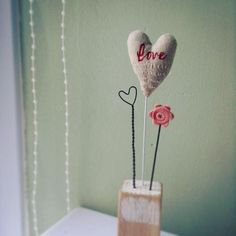 two hearts are placed in a vase with flowers on the top and one is made out of wood