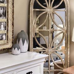 a white dresser topped with a mirror next to a lamp and vase on top of it