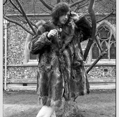 a woman standing next to a tree wearing a fur coat