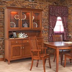 a wooden dining room table and chairs in front of a brick wall