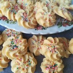 some cookies with sprinkles are on a white plate and blue tablecloth