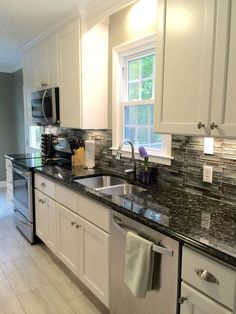 a kitchen with white cabinets and granite counter tops, stainless steel appliances and dishwasher