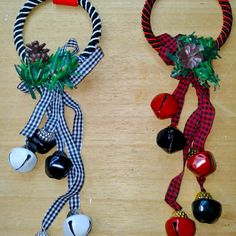 two christmas wreaths with bells and ornaments hanging from them on a wooden table top