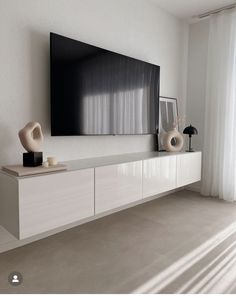 a flat screen tv mounted to the side of a white wall in a living room