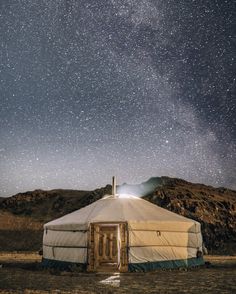 a yurt in the middle of nowhere at night with stars above it and an open door