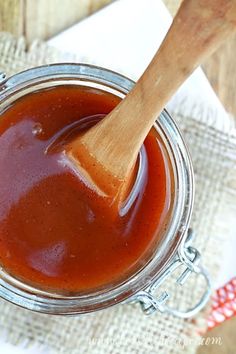 a wooden spoon in a glass jar filled with bbq sauce on a cloth napkin