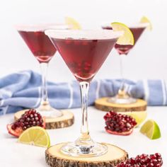 three wine glasses filled with pomegranate and garnished with lime slices