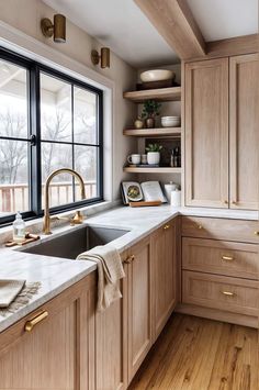 a kitchen with wooden cabinets and white counter tops, gold faucet, open shelving