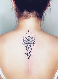 the back of a woman's neck with a lotus tattoo on her left shoulder