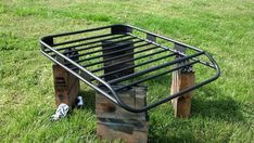 a metal bed frame sitting on top of wooden pallets in the middle of grass