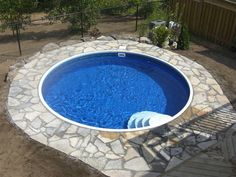 an above ground swimming pool in a backyard with stone steps leading up to the side