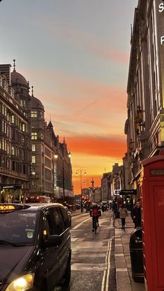 a city street with cars and people walking on the side walk at sunset or dawn